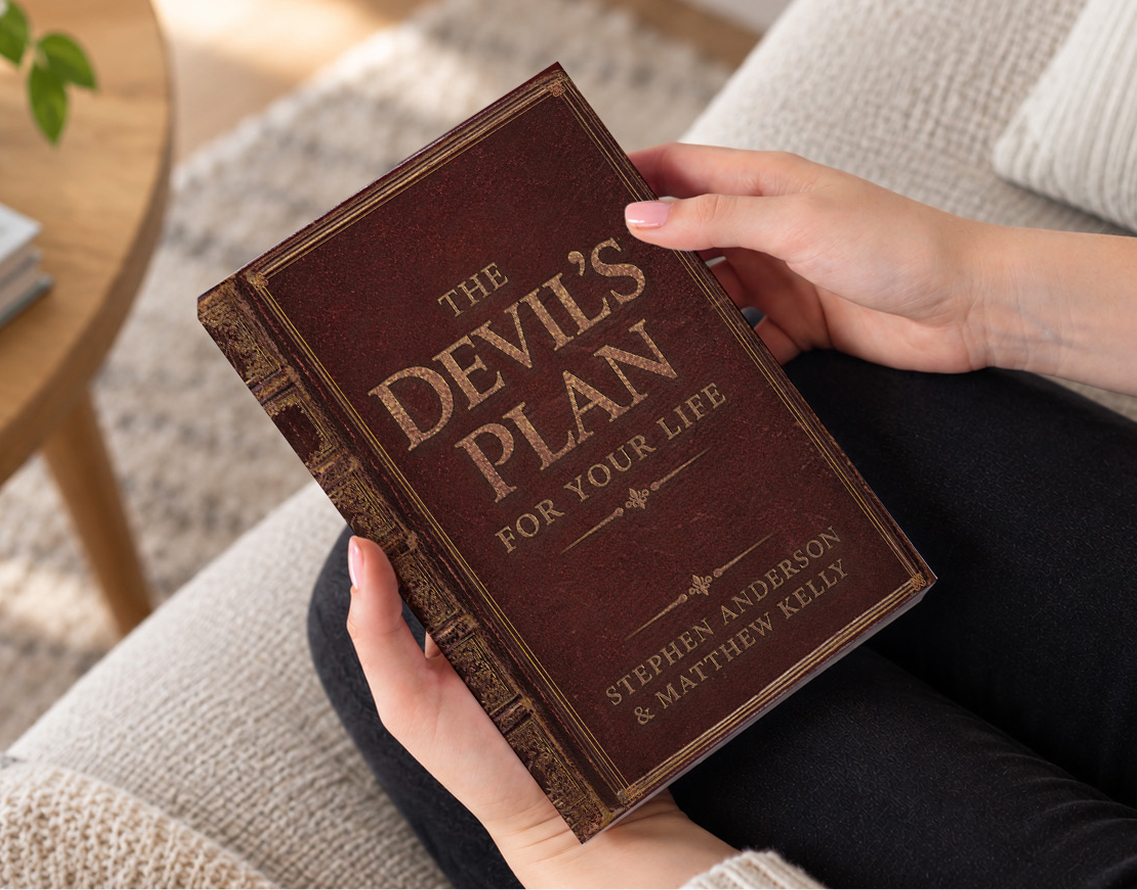 Image of a person hold The Devil's Plan for Your Life in their lap sitting on the couch with a coffee table in front of them.